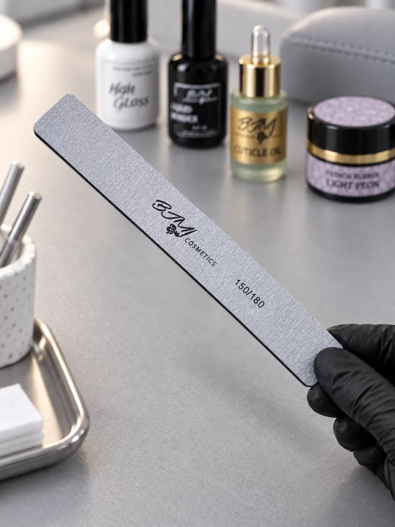 BJM Cosmetics dildė S3 150/180 grit, laikoma rankoje su juoda pirštine